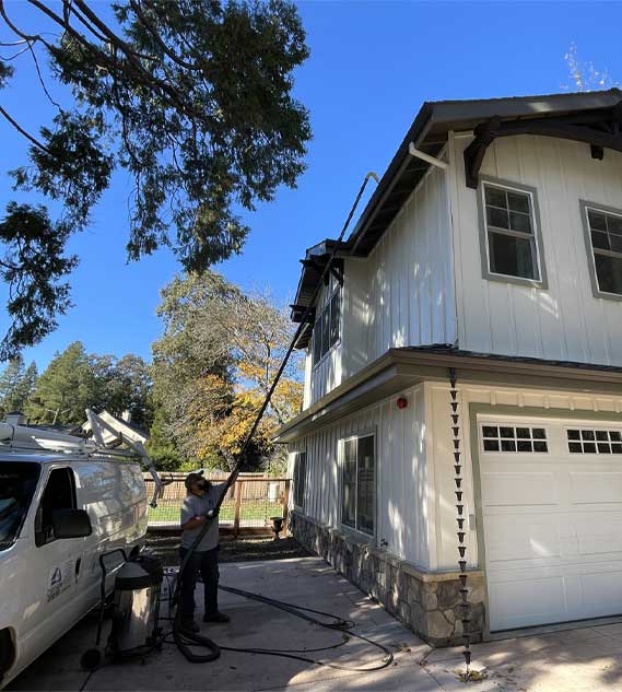 Man cleaning gutters with Cyclone Triple 3600 and 20 foot Carbon Clamping pole.