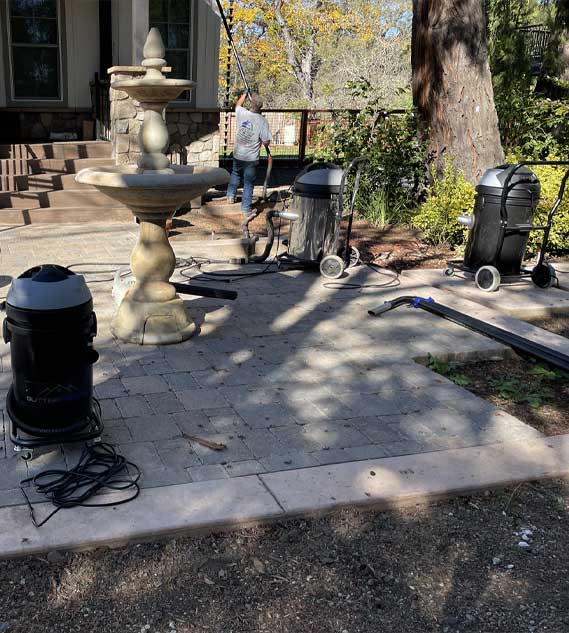 A man testing GutterProVac cyclone vacuums for gutter maintenance on a home.