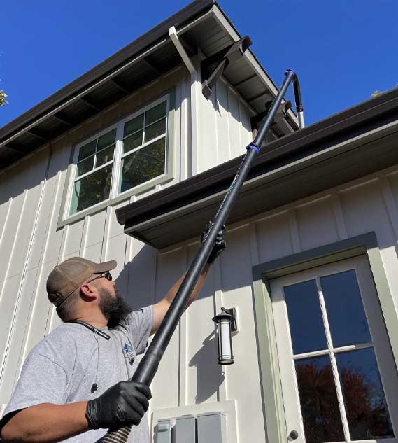 A man doing gutter cleaning on a house using the carbon clamping pole and carbon swan neck.