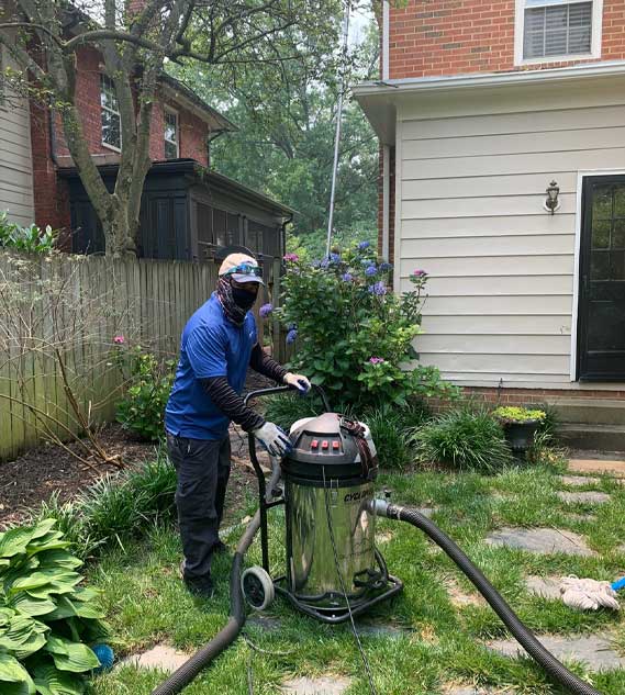 A worker in a backyard getting the Cyclone Triple 3600 vacuum ready for use.