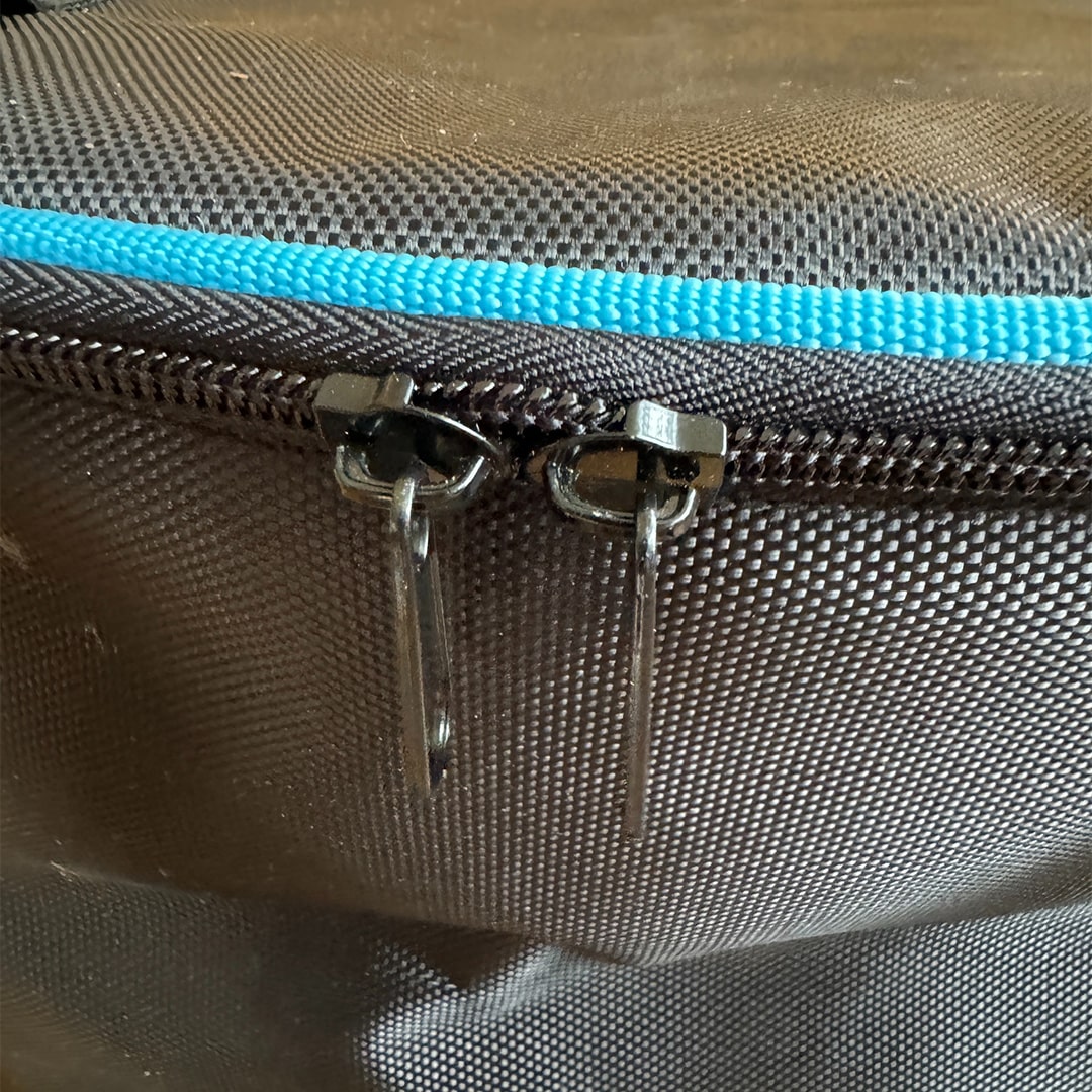 Close-up view of Cyclone hose bag showing dual zippers, blue trim, and tightly woven black fabric