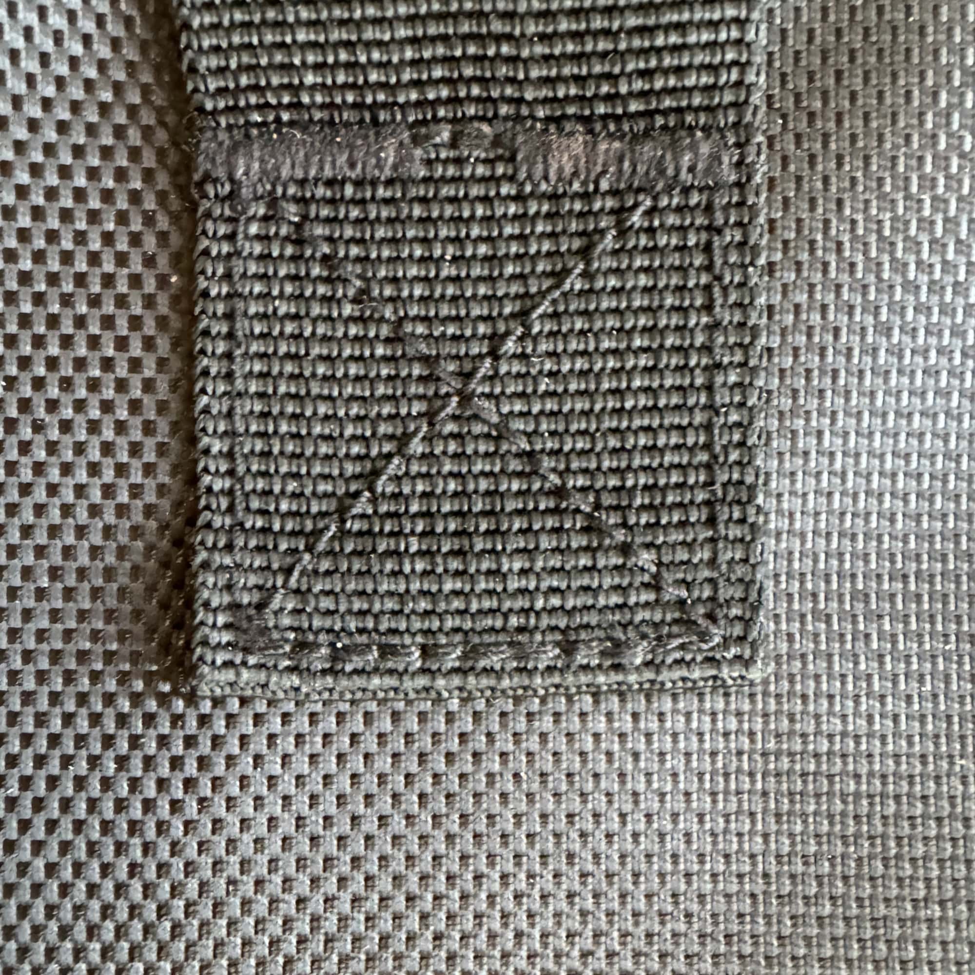 Flat-angle close-up of reinforced X-stitch on nylon strap of Cyclone vacuum hose storage bag